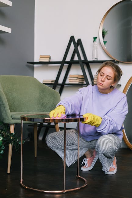 A person dressed in protective clothing and gloves is using a vacuum cleaner with a floor attachment to perform surface cleaning on a smooth, hard floor. The vacuum cleaner is positioned nearby, and the person is handling the cleaning equipment with both hands, indicating a thorough approach to deep cleaning or sanitisation in a commercial or residential space. The setting appears well-lit, emphasizing the cleanliness and maintained condition of the area. This image exemplifies professional cleaning practices, as offered by companies like Cleaners TW9, aligned with their Richmond Hill end of tenancy cleaning services, TW9.